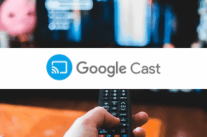 
A white horizontal banner is centered over a blurred image of a hand holding a black remote control, pointing towards a blurred television screen in the background. The TV screen displays colorful, indistinct content.

Superimposed on the center of the white banner is the "Google Cast" logo. It features a blue icon on the left, which is a stylized rectangle with three curved lines emanating from its bottom left corner (representing a screen with a Wi-Fi signal).